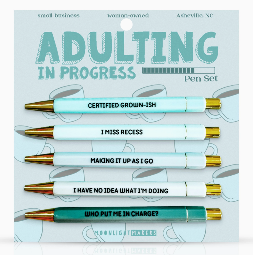 Pen set with humorous phrases on packaging labeled 'Adulting in Progress'.