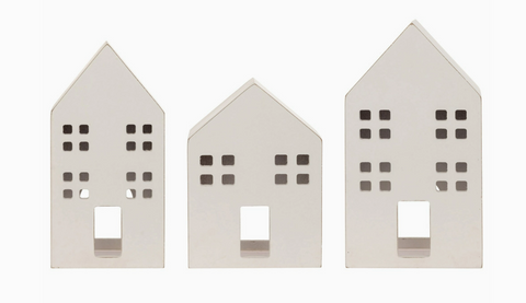 Three white house-shaped candle holders on a white background